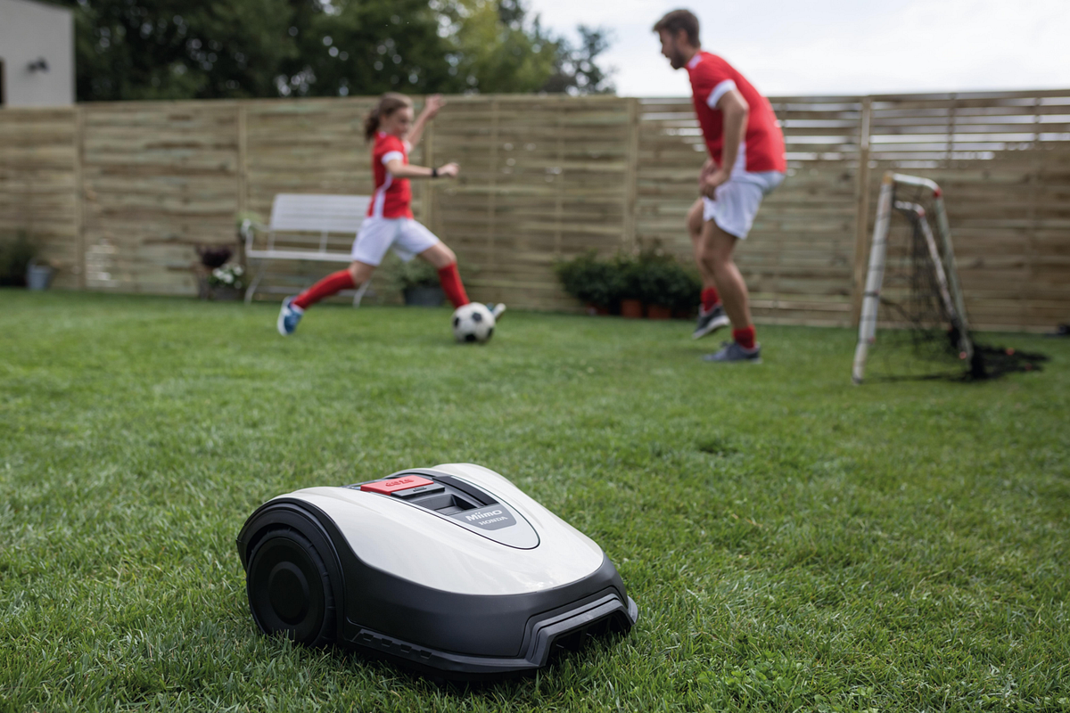 Rasenmähroboter und spielende Kinder im Garten