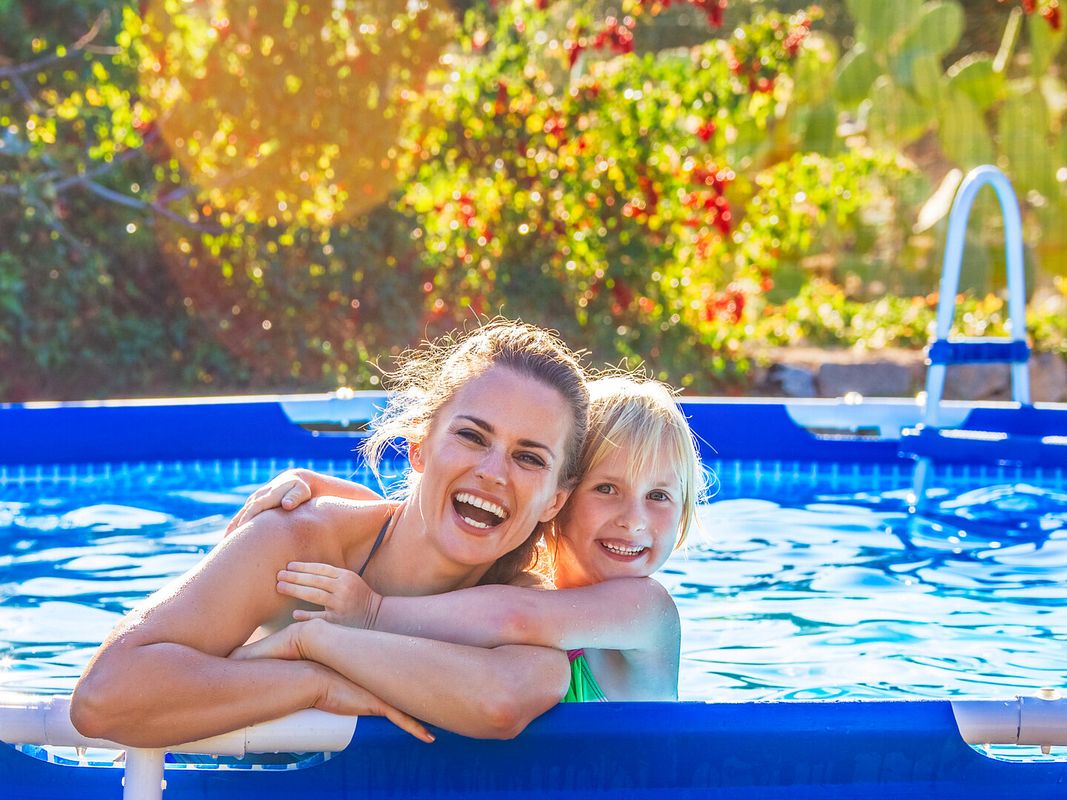 Mutter und Tochter plantschen in einem Aufstellpool 