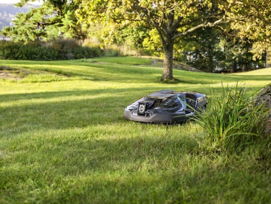 Rasenmähroboter im Halbschatten auf schön gepflegtem Rasen
